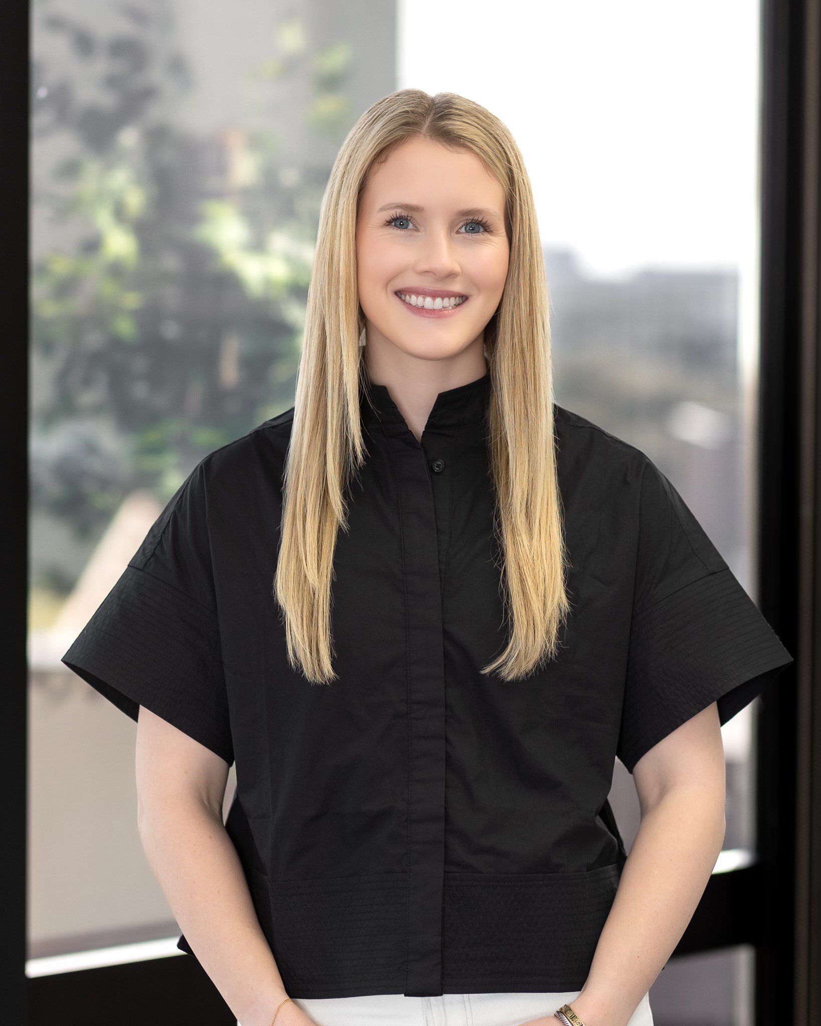 Lucy A woman in black shirt standing next to window.
