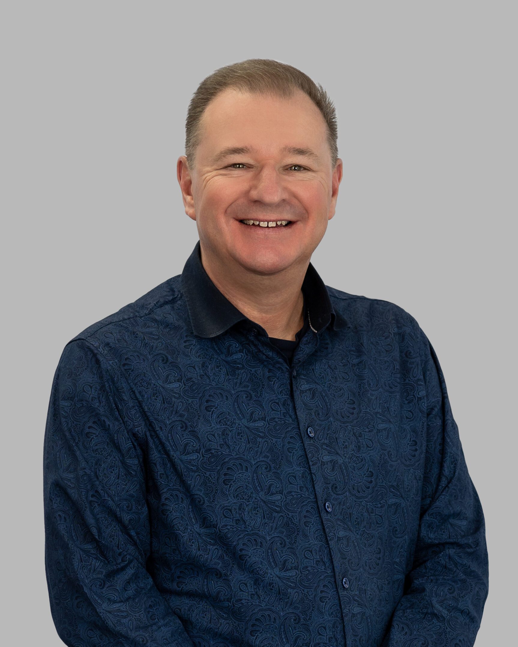 A man in a blue shirt is smiling for the camera.