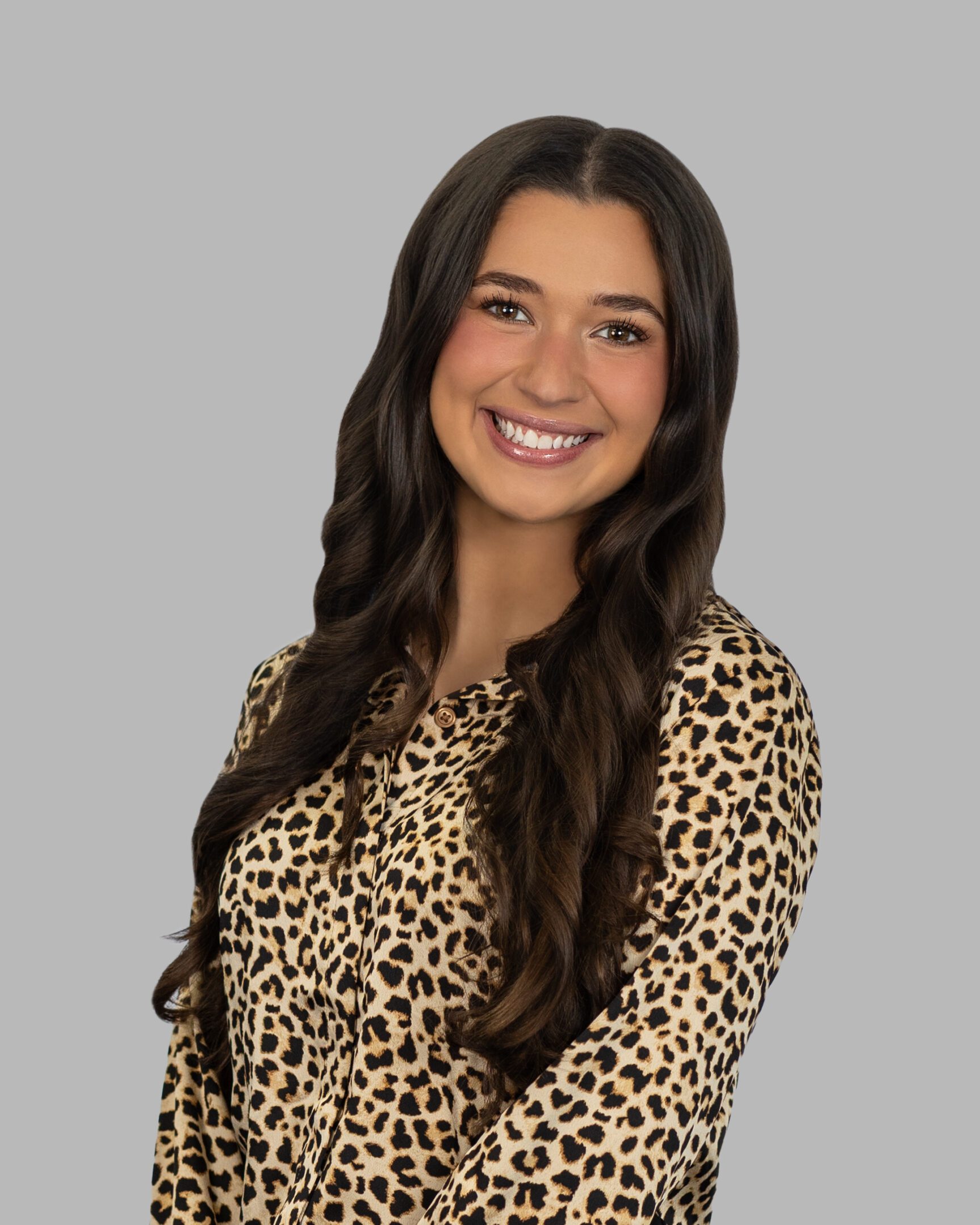 A woman in leopard print shirt smiling for the camera.