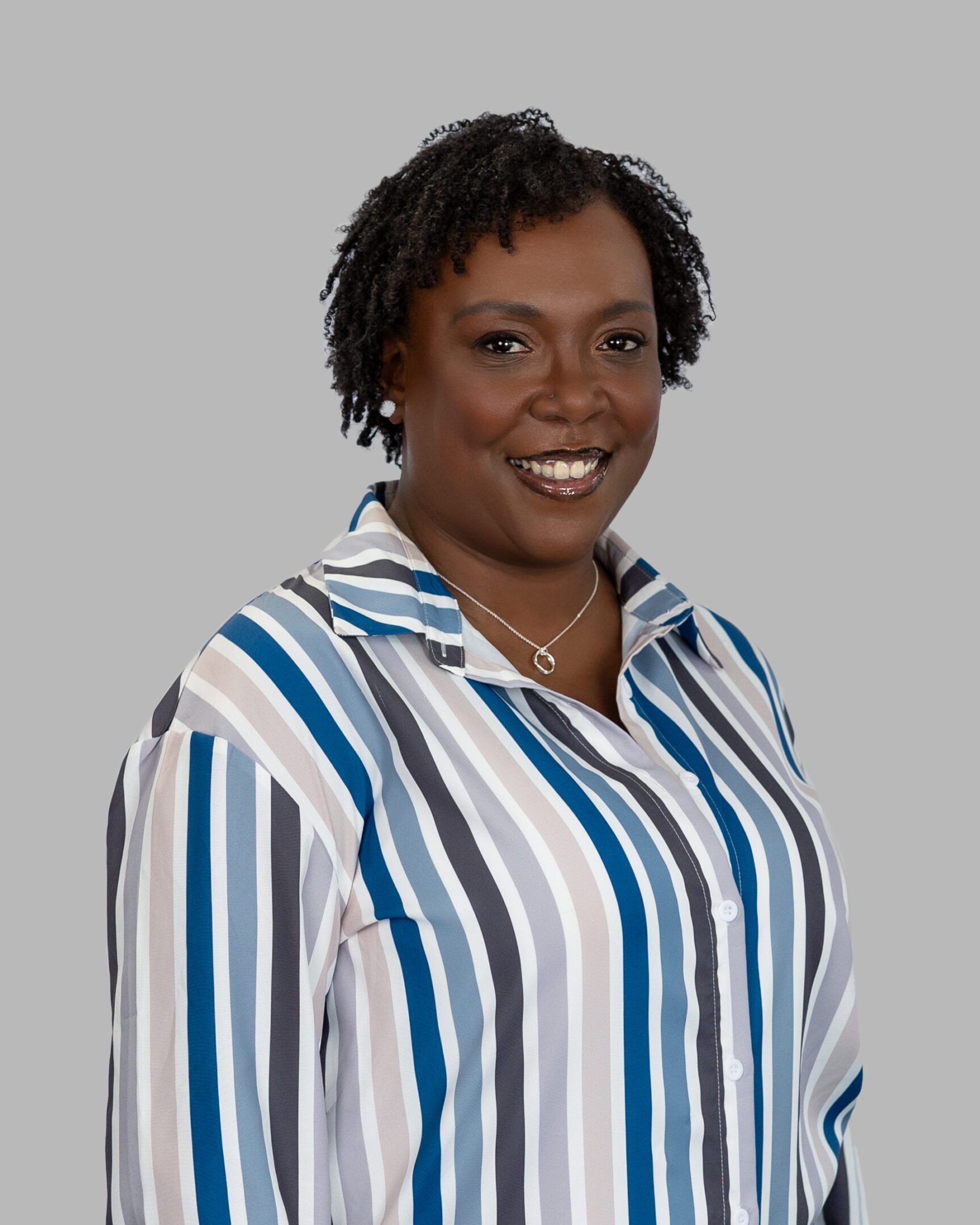 Desireé_Watts-59-Print A woman in striped shirt smiling for the camera.