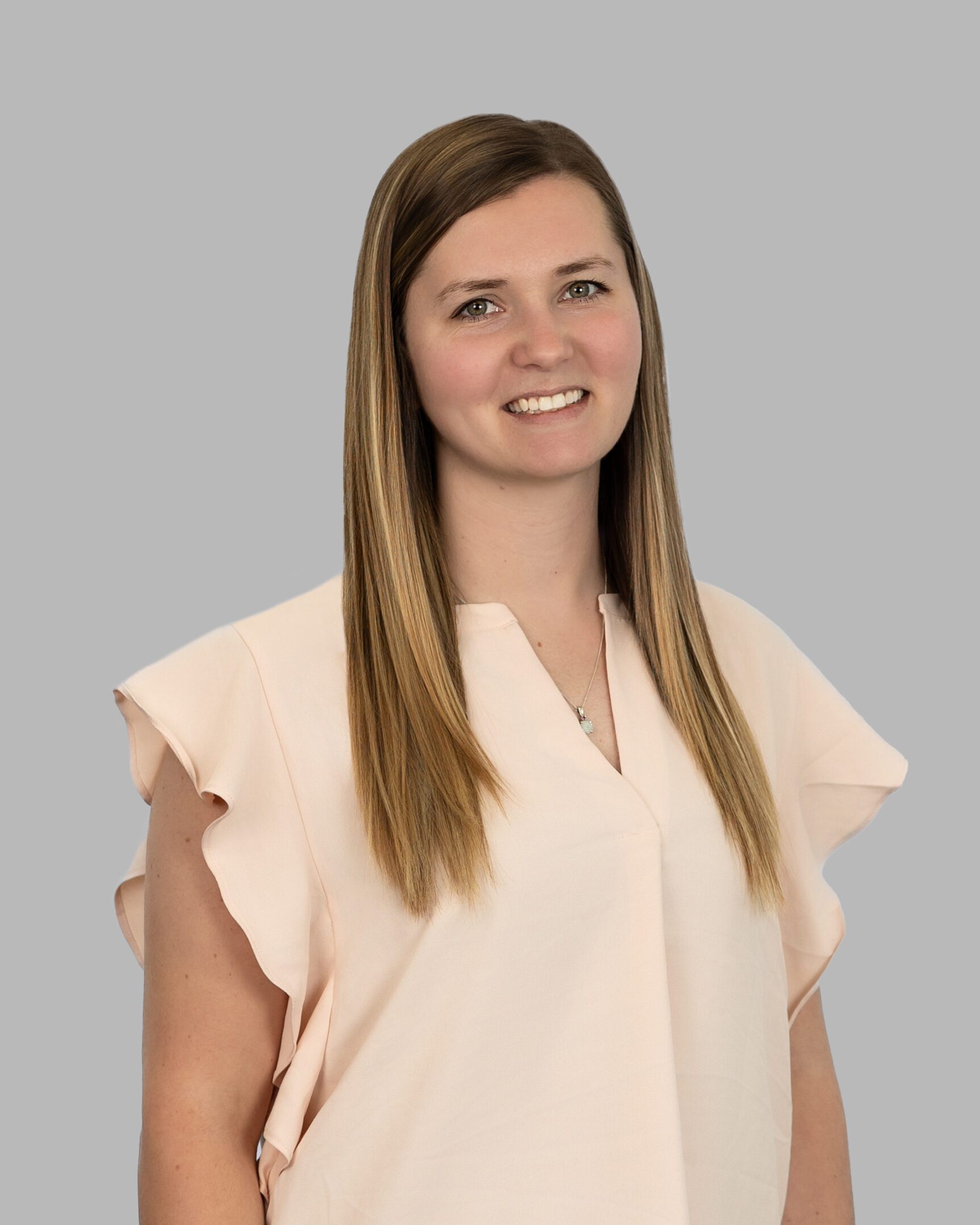 A woman in a pink shirt smiling for the camera.